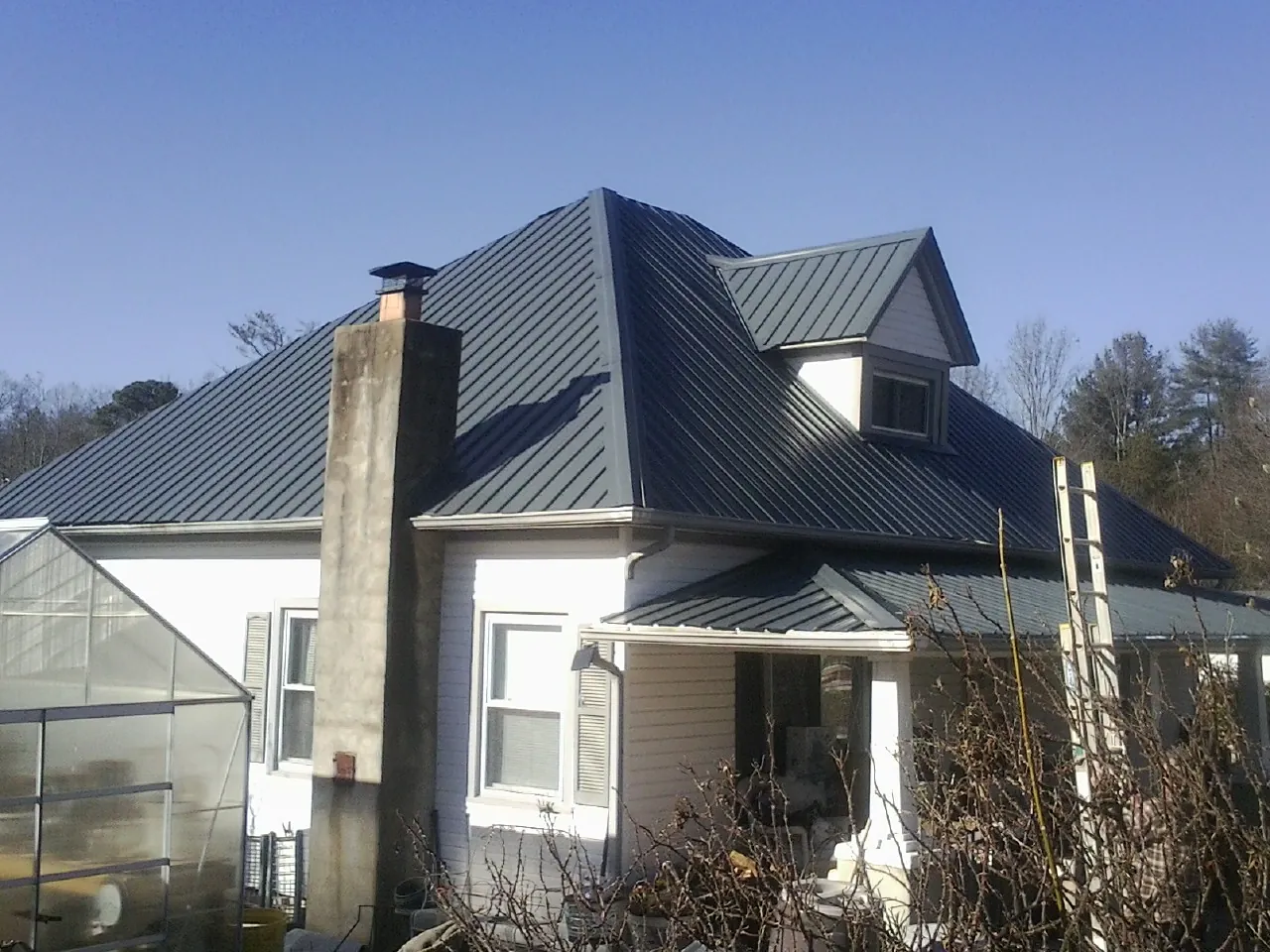 Dark blue standing seam metal roof on a white farmhouse with dormer — Slate & Tile Roof Repair by Roofing Brothers in Powell