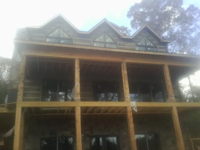 Dormers and porch framing on a large log home under construction — Roof Coating work by our crew in Powell