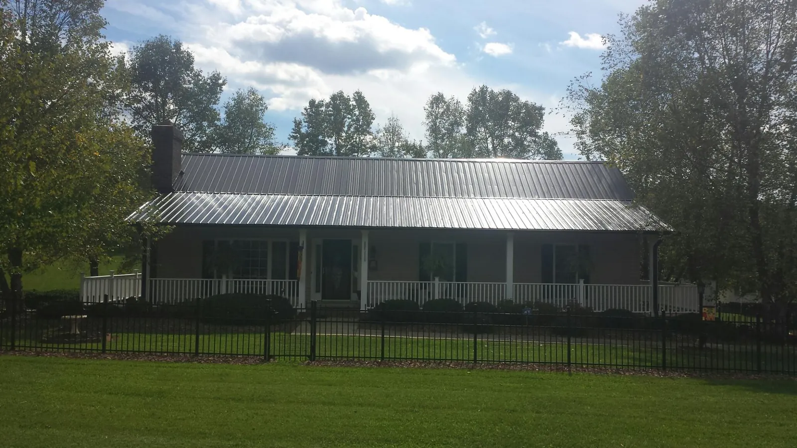 Gray metal roof on a brick ranch with a full width front porch — Gutter Guard Installation work by our crew in Powell
